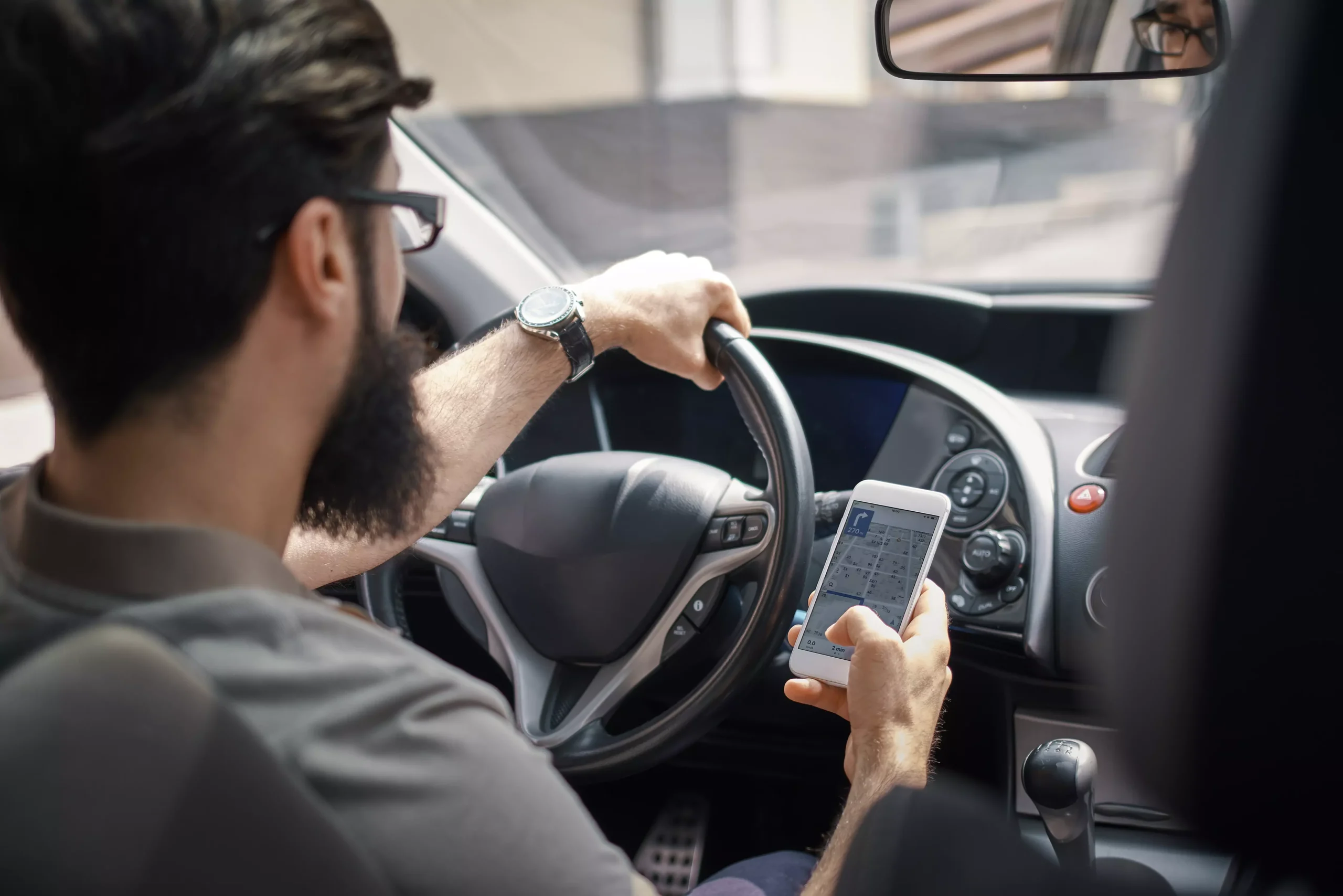 Driver holding a phone searching for route in map app